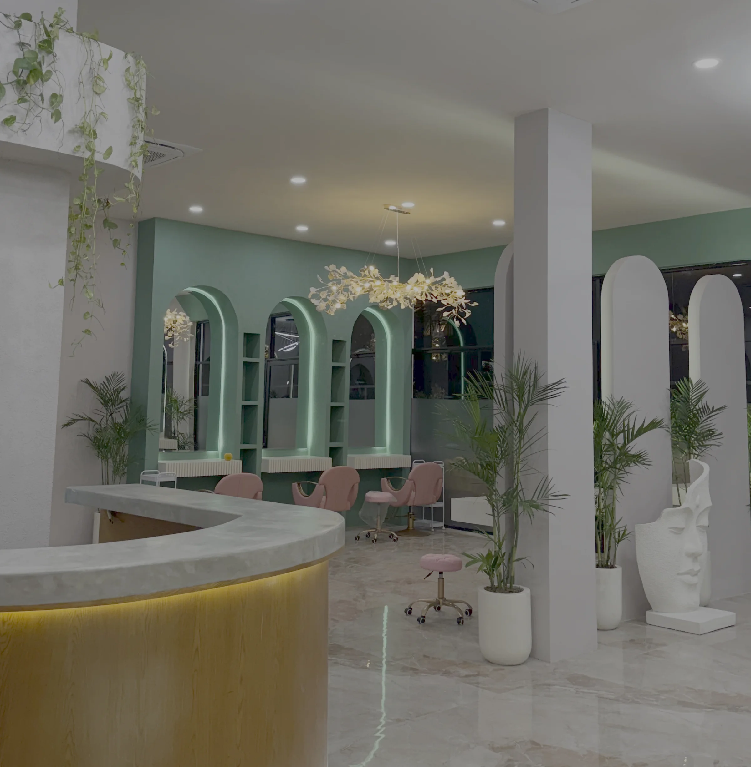 Rose Petal salon interior — sage green art deco arches, rose chairs, gold accents, marble floors and tropical plants